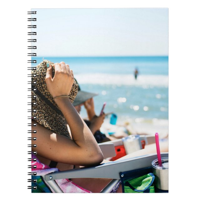 Woman lying on sun lounger covering her face with  notebook (Front)