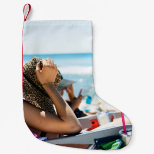 Woman lying on sun lounger covering her face with small christmas stocking
