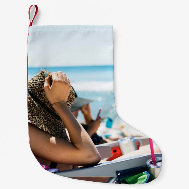 Woman lying on sun lounger covering her face with  small christmas stocking (Front)