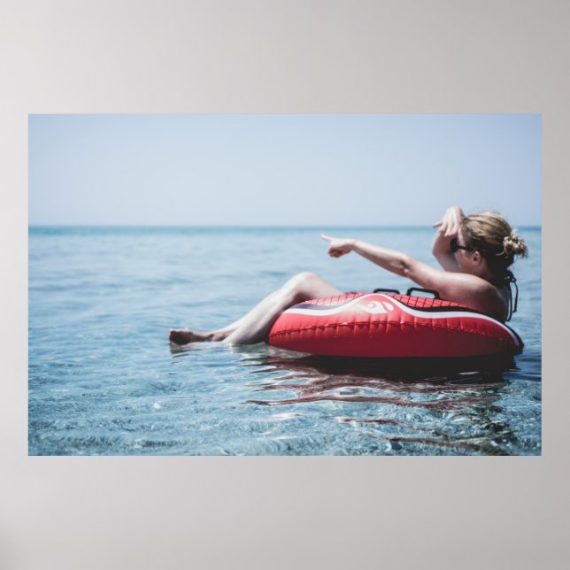 Woman on an inflatable float in the ocean pointing poster (Front)