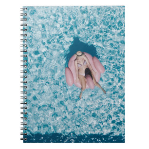 Woman on pink buoy surrounded by body of water in notebook