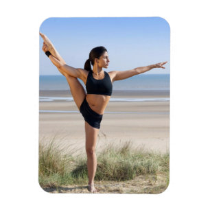 woman practicing yoga on beach wearing magnet