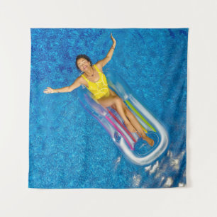 Woman riding on plastic floating buoy on body of w tapestry