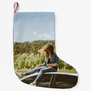 Woman sitting on roof of white sedan small christmas stocking