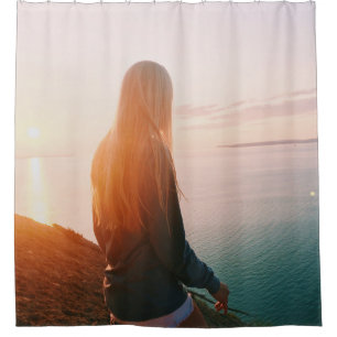 Woman stands near body of water during golden hour
