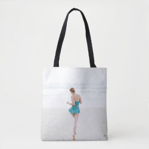 Woman walking on shore near beach tote bag
