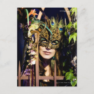 Woman wearing a mask looking out from and iron postcard