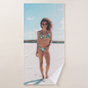 Woman wearing bikini standing on sand bath towel