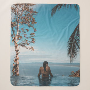 Woman wearing black bikini tap swimming on body of sherpa blanket