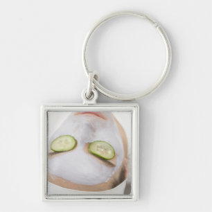 Woman with face mask and cucumber slices on keychain