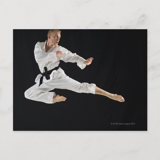 Young man performing karate kick on black postcard (Front)