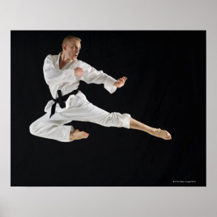 Young man performing karate kick on black poster