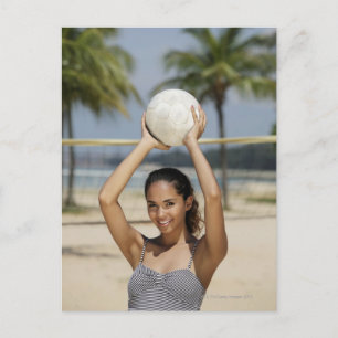 Young woman holding volleyball and smiling at postcard