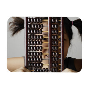 Young woman peering through abacus. magnet